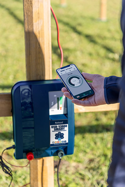 A farmer controls his ESD 12000 Smart Energiser electric fence  device using an app on his mobile phone